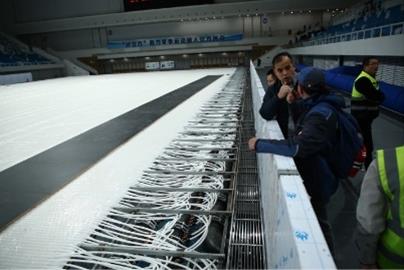 People along side of an exposed underside of the ice rink