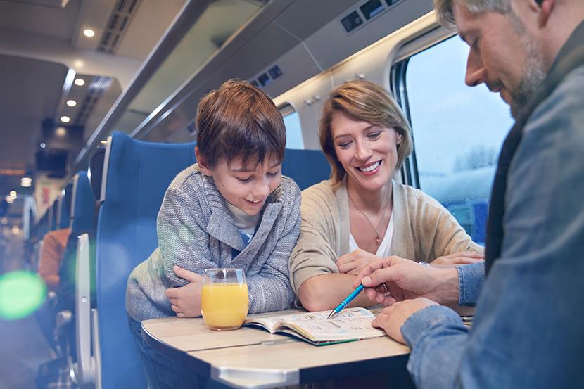 sitting man woman and child looking at a book on a passenger train