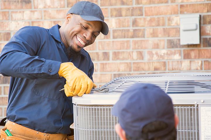 two men working on an air conditioning unit outside